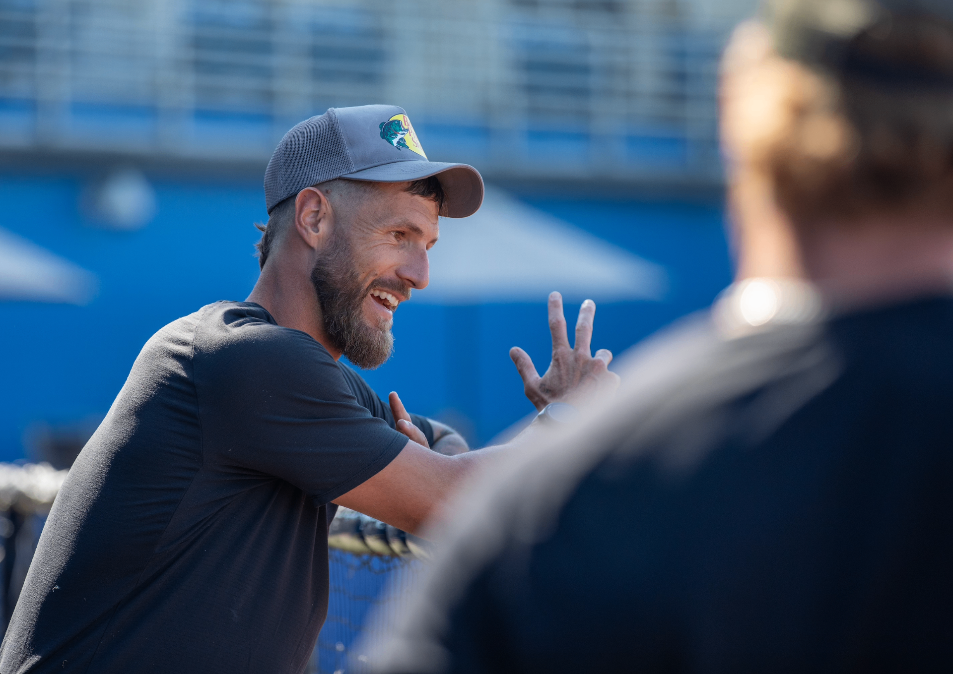 Shane Greene smiling and coaching a player at the cage